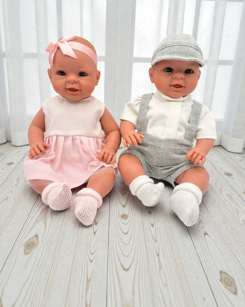 Spanish artisan-crafted baby dolls in grey herringbone and pink dress showing anatomically correct boy and girl options