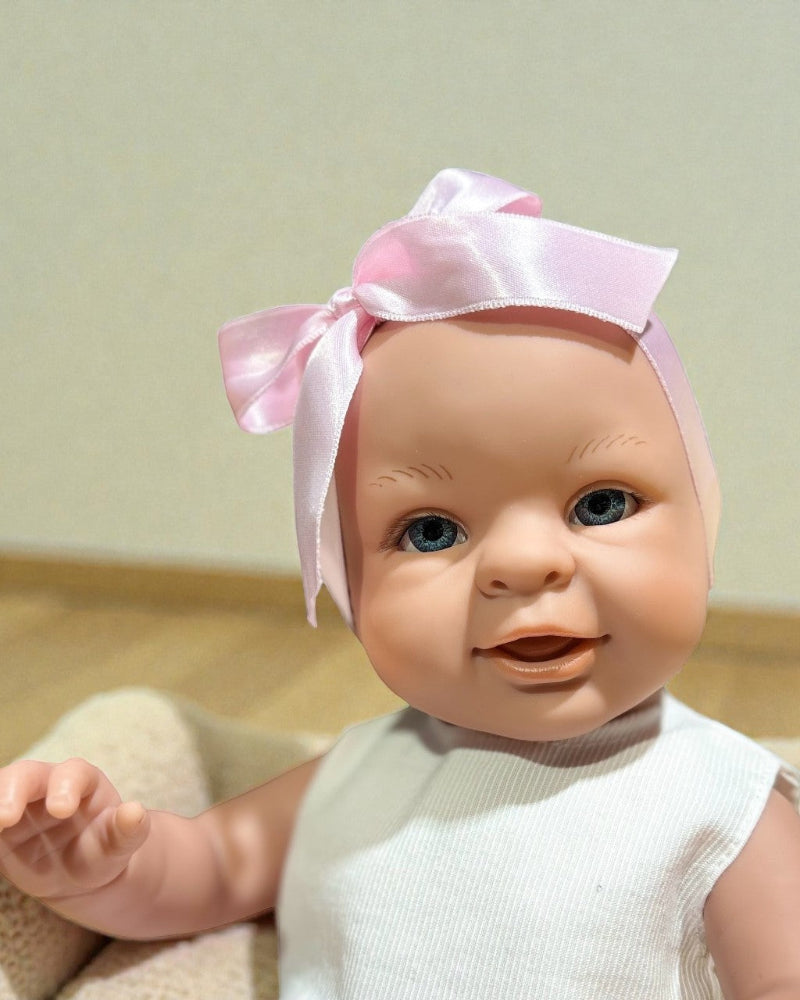 Girl Bebenita doll with blue eyes in pink dress and white ribbed top with ribbon