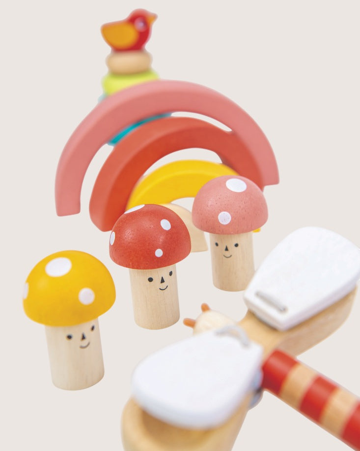 Wooden toy set with rainbow, mushrooms, and a cloud on a light background