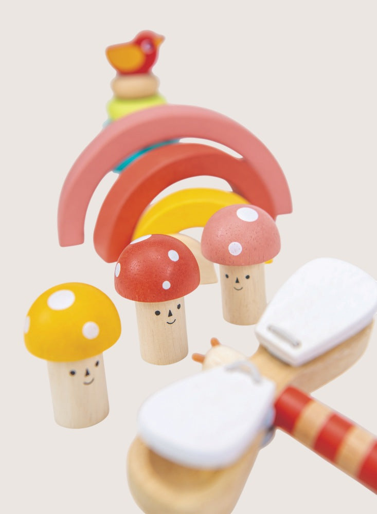 Wooden toy set with rainbow, mushrooms, and a cloud on a light background