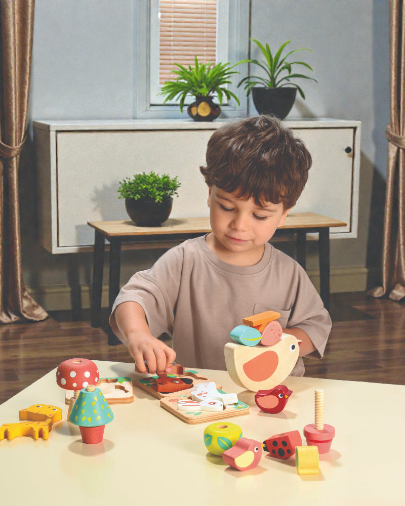 Child playing with wooden toys at a table in a room with plants and furniture.