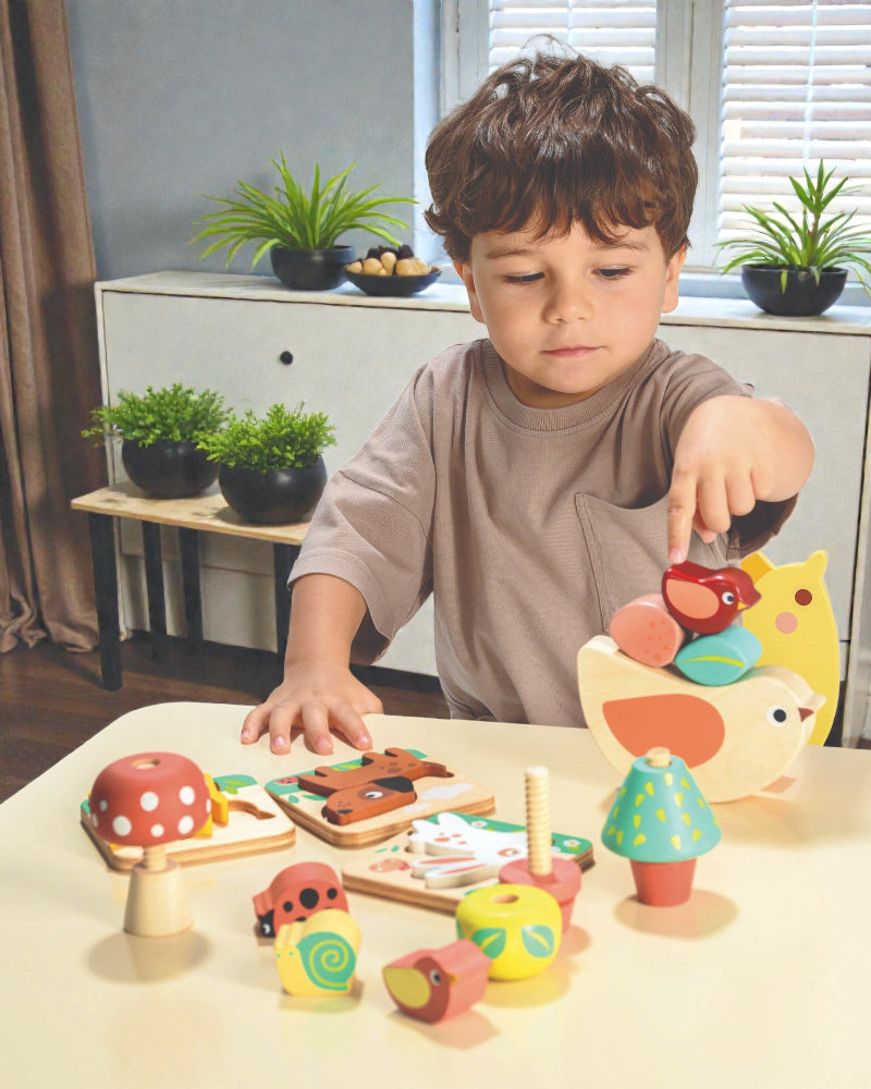 Child playing with wooden toys on a table in a room with plants and furniture.