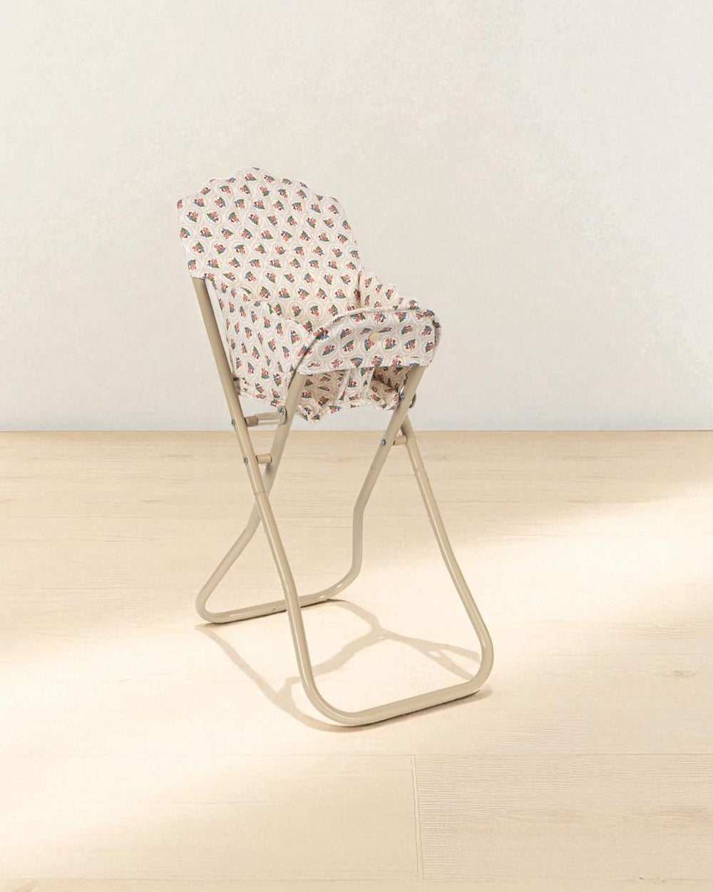 Cream-colored doll feeding chair showing coral and teal rose print with stable base design