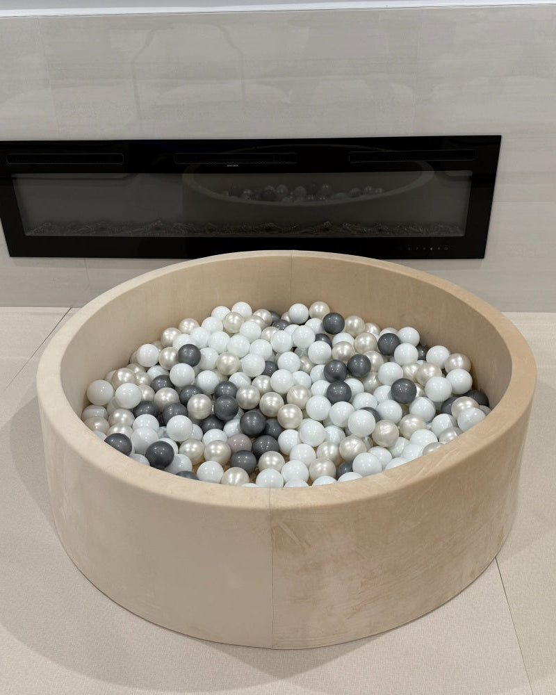 ball pit filled with multicolored balls in front of a modern fireplace.