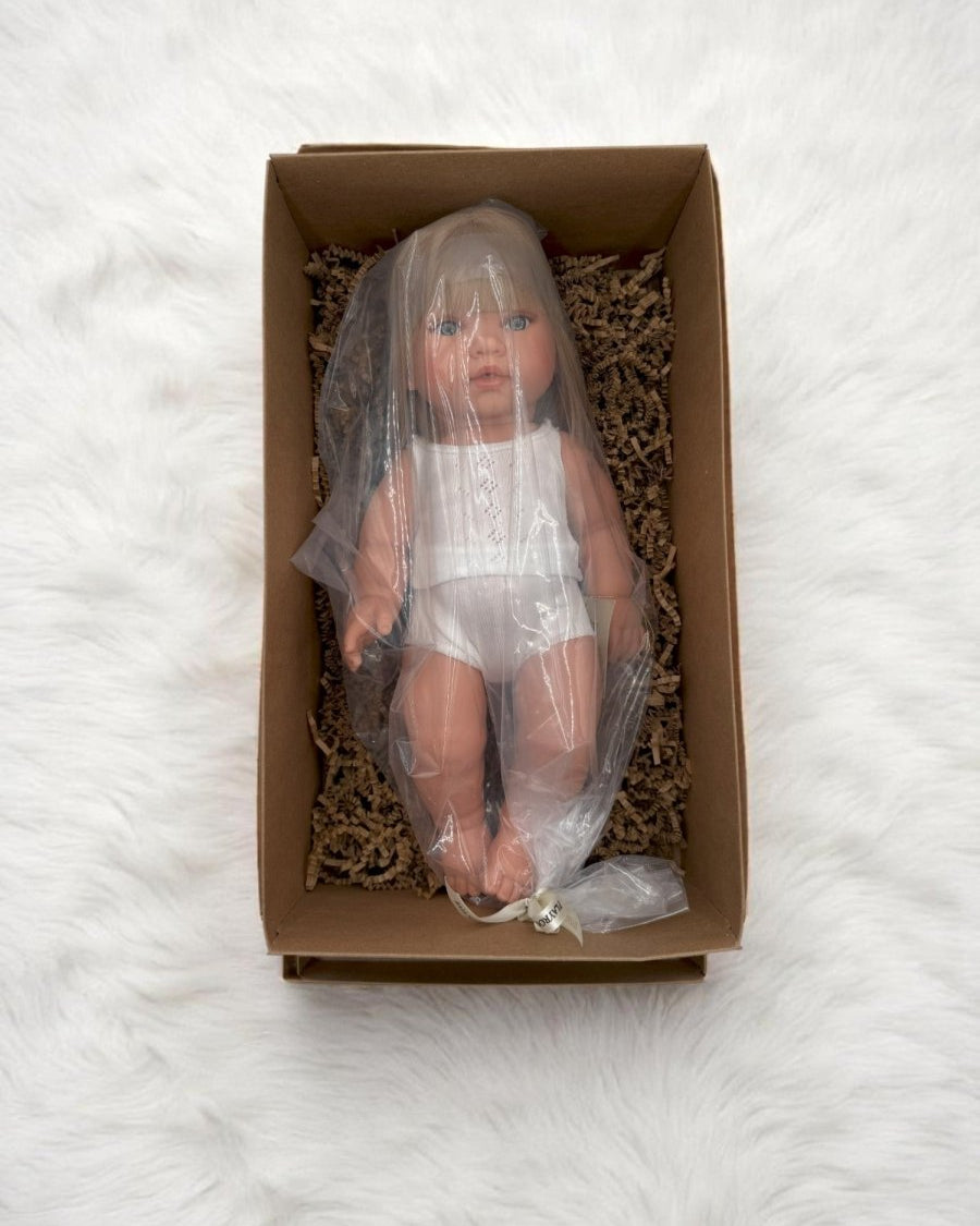 Blue-eyed realistic baby doll with blonde bob in classic white outfit