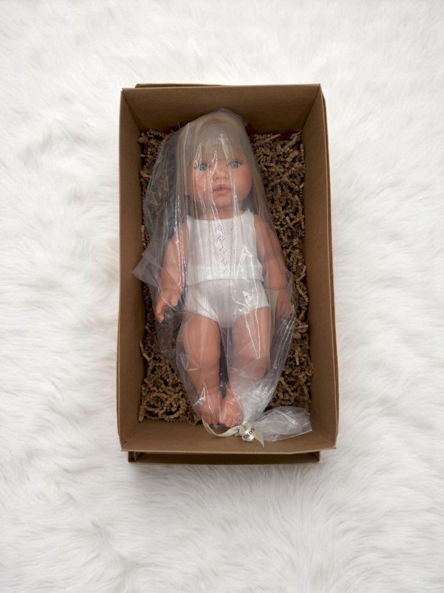 Blue-eyed realistic baby doll with blonde bob in classic white outfit