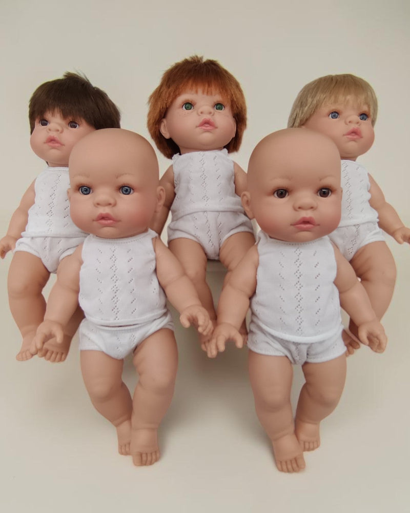 Five dolls in white outfits on a plain background