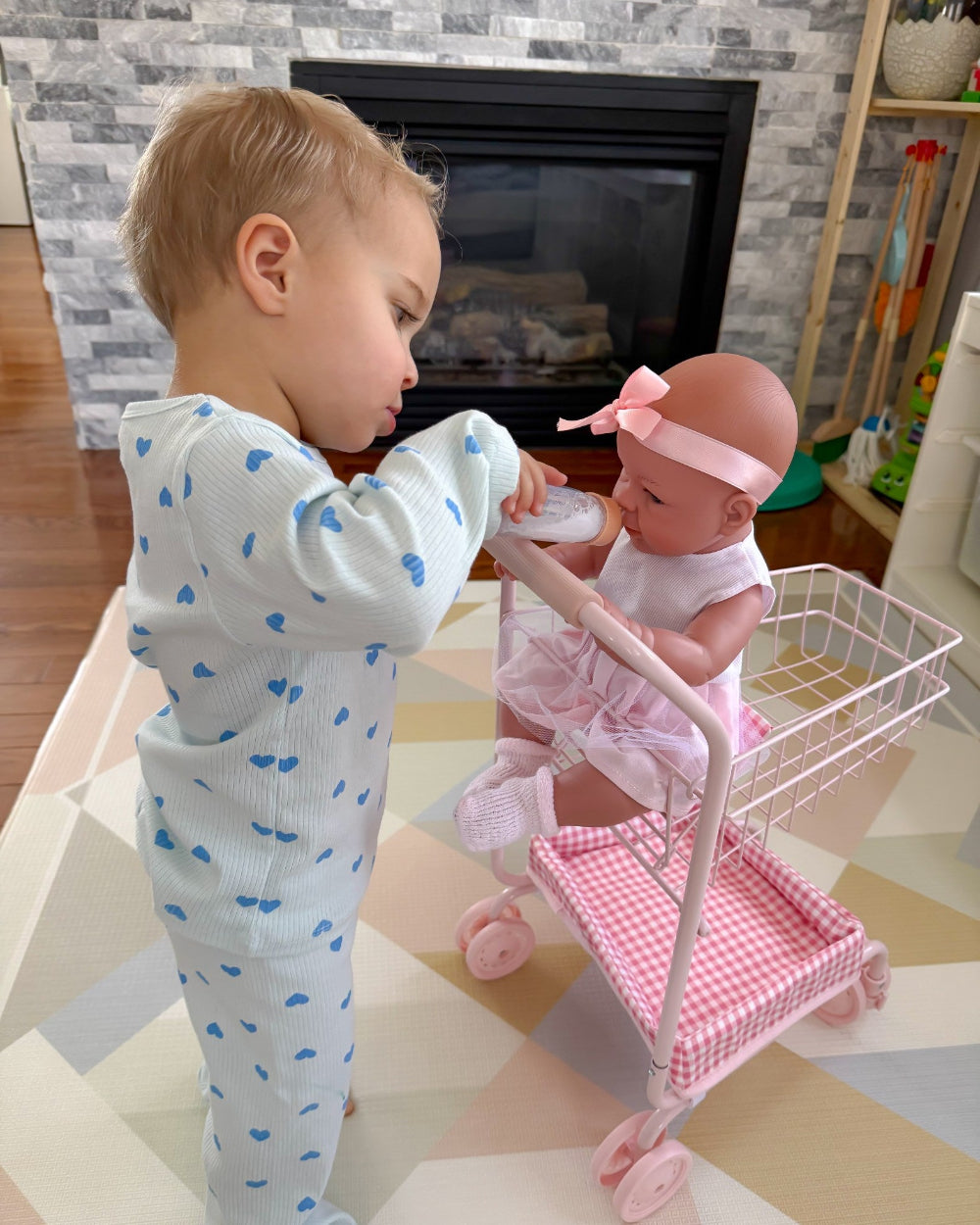 Child playing with a doll in a toy cart in a home setting