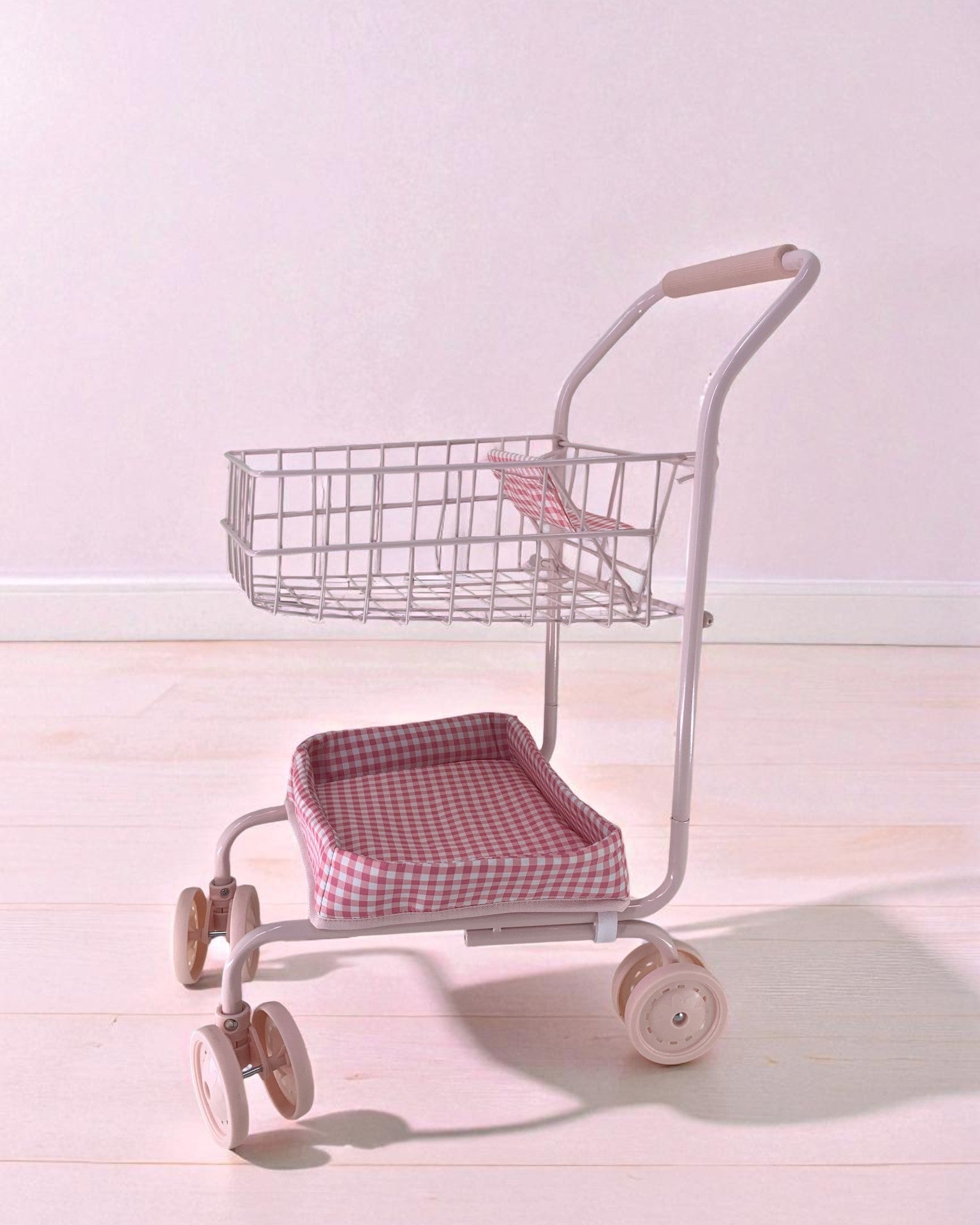 Side view of pink gingham doll cart showing two-tier design with upper basket and padded lower seat platform