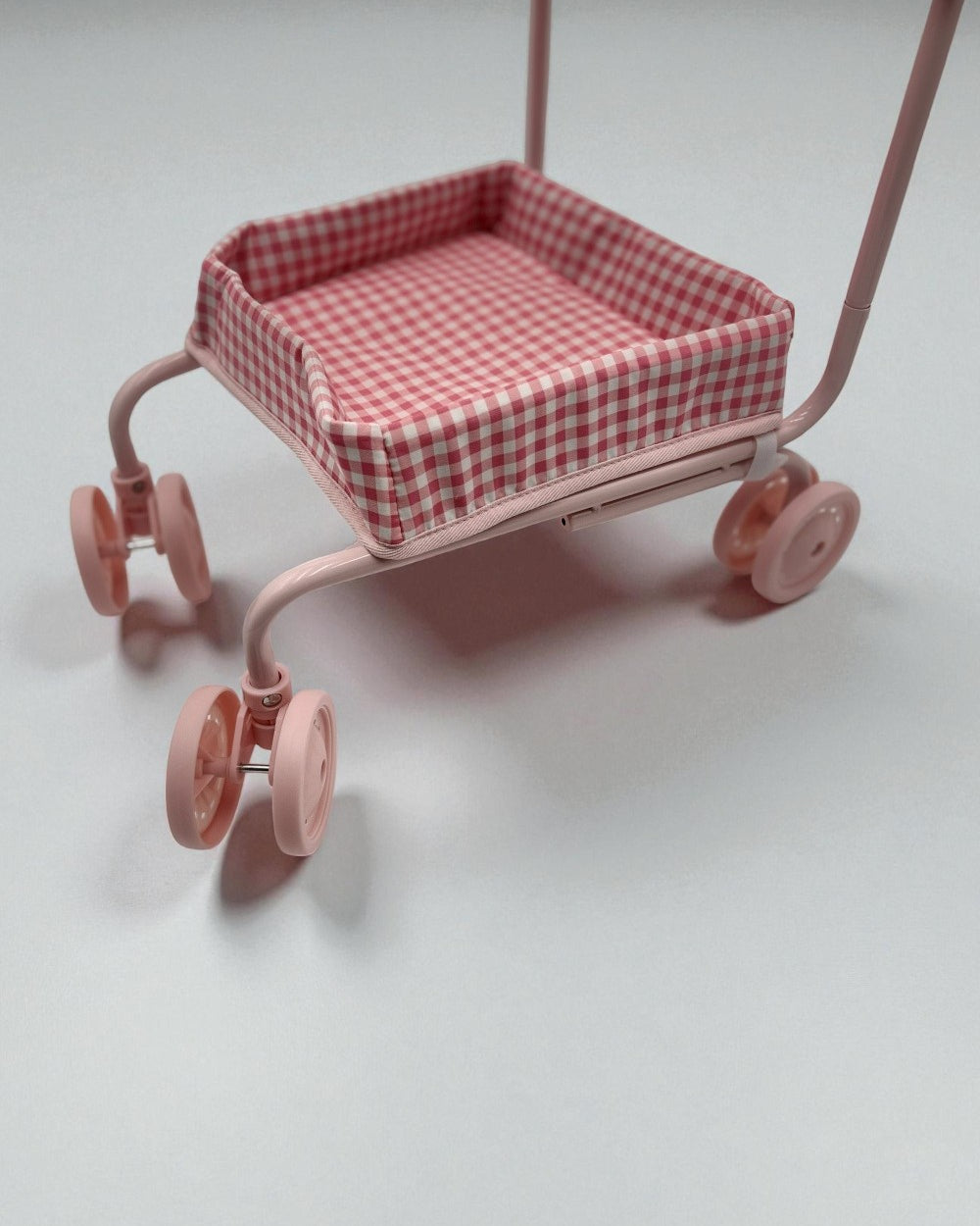 Pink toy cart with a checkered seat on a light gray background
