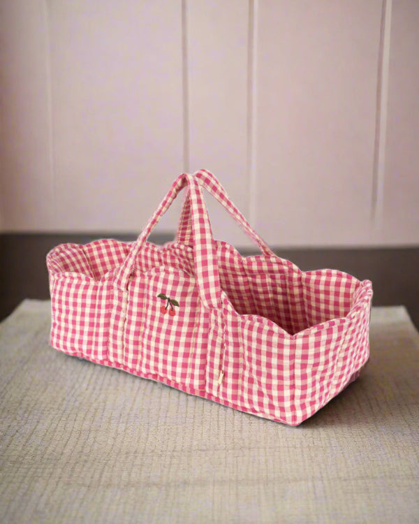 Pink gingham doll bassinet with classic checkered pattern and sturdy carrying handles