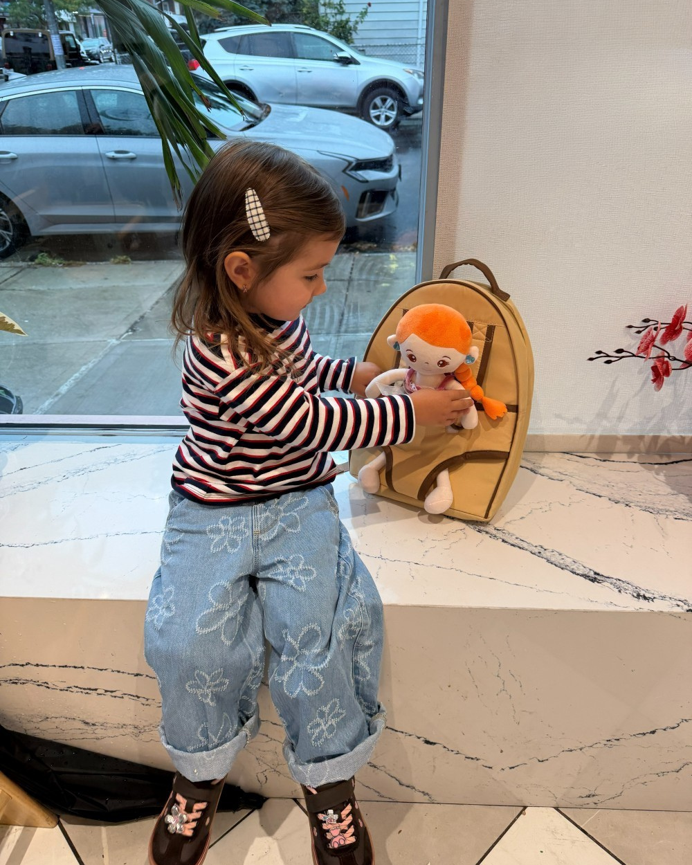 Child tucking in doll in the little carrier