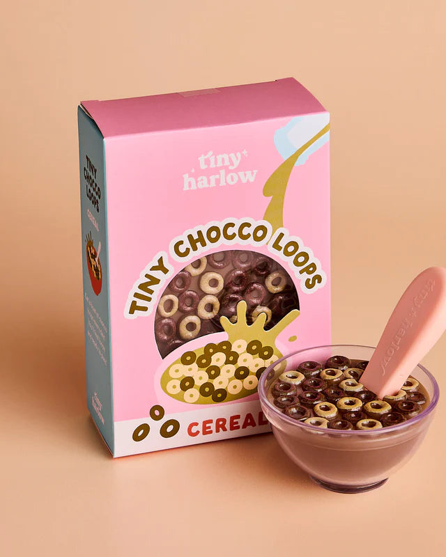 Tiny Harlow cereal box with a bowl of cereal and spoon on a beige background