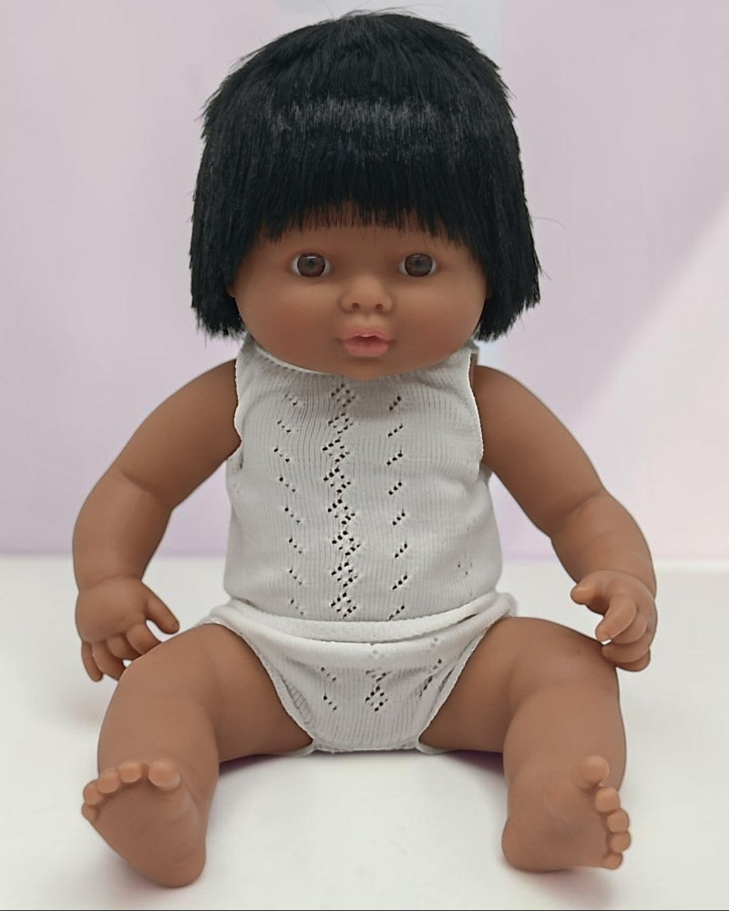 Doll with black hair wearing a white lace outfit on a white background