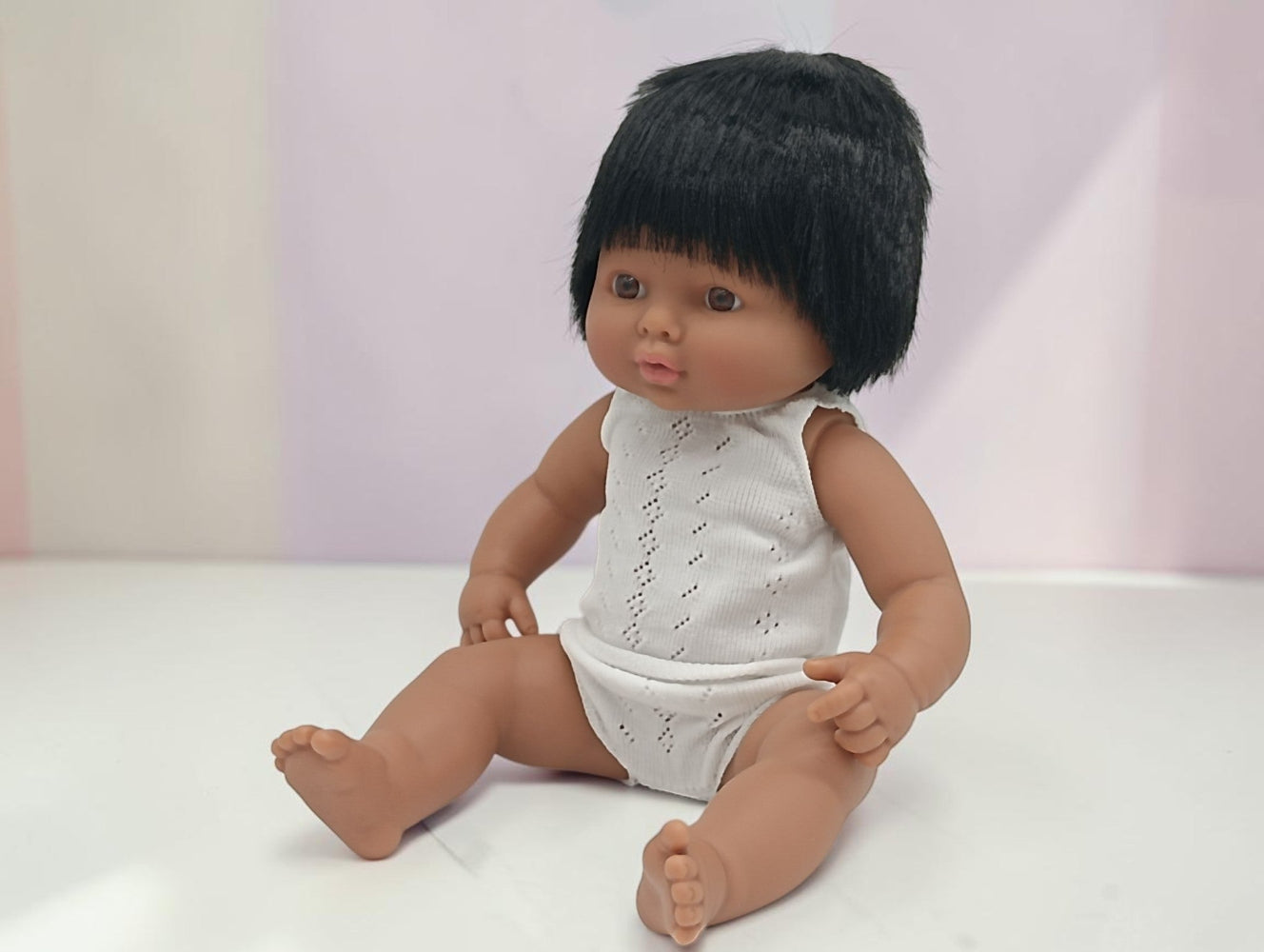 Doll with black hair wearing a white outfit on a light background