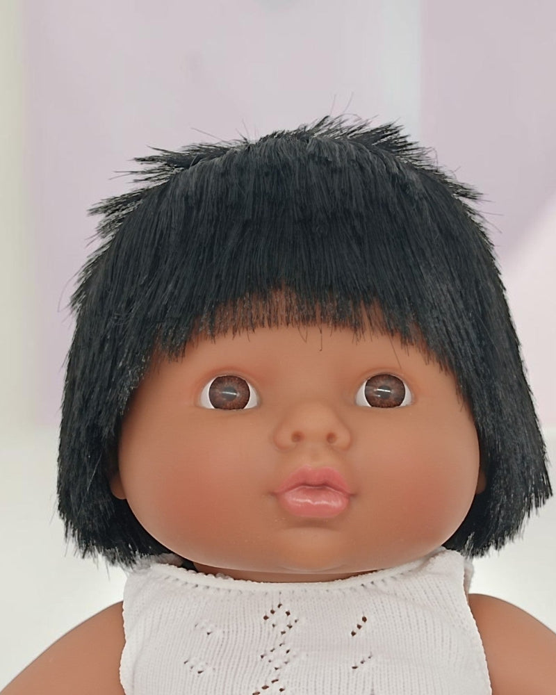 Doll with black hair and a white outfit on a light background