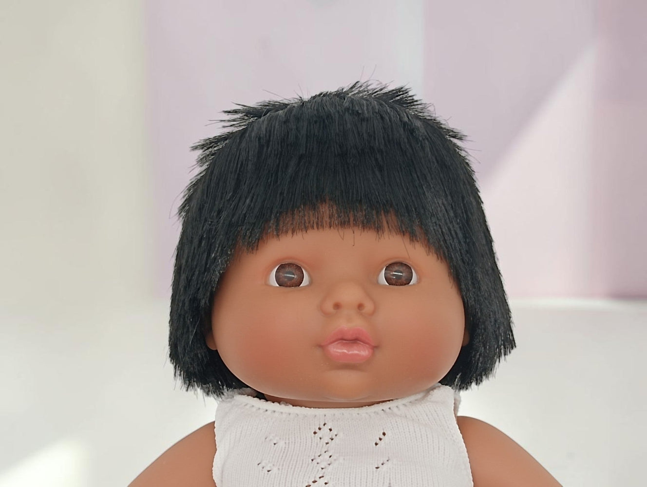Doll with black hair and a white outfit on a light background