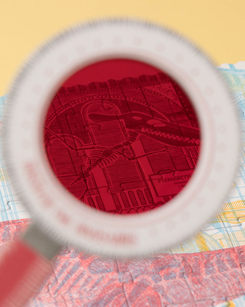 Red textured object under a magnifying glass on a colorful map background