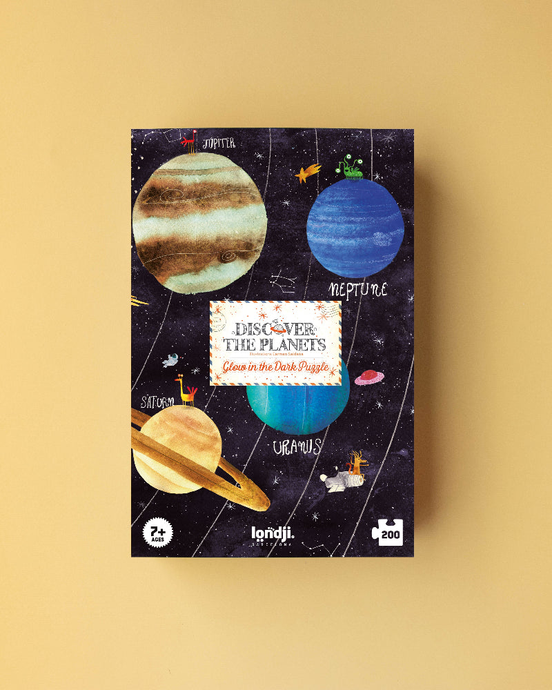 Jigsaw puzzle box with planet illustrations on a beige background