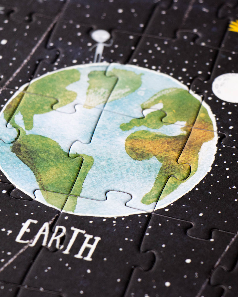 Jigsaw puzzle piece with Earth illustration on a space-themed background