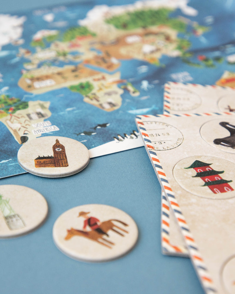 World map with travel-themed coasters and a notebook on a blue surface