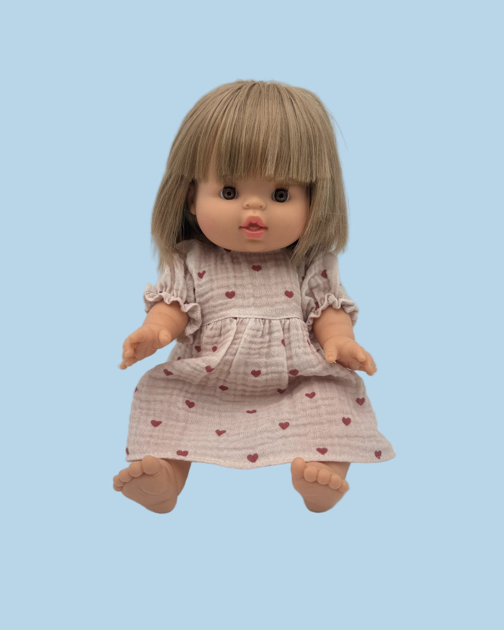 Doll wearing soft cotton muslin dress in mauve heart pattern matching Leni & Romi collection