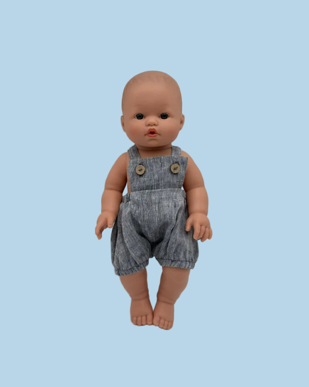 Bebenita doll wearing handmade chambray muslin overall with functional buttons, standing against white background
