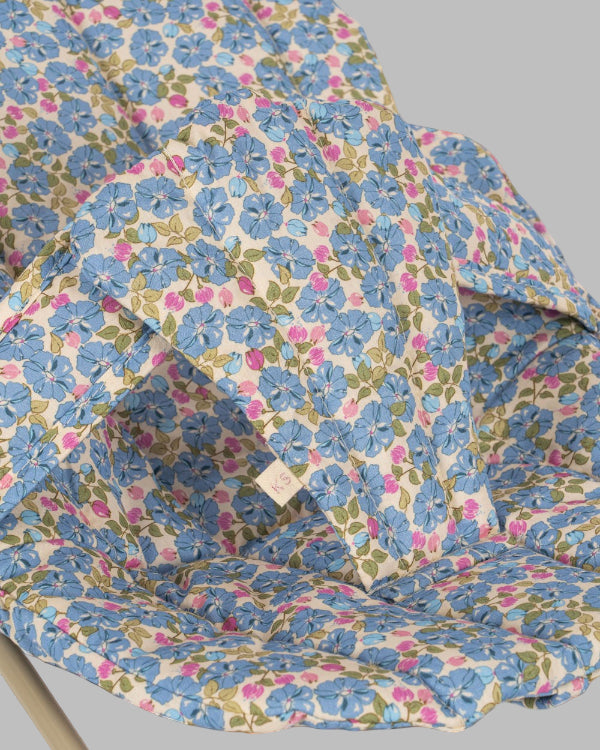 Close-up of Fleur Rosier print fabric showing cornflower blue flowers with pink accents and green leaves on cream background