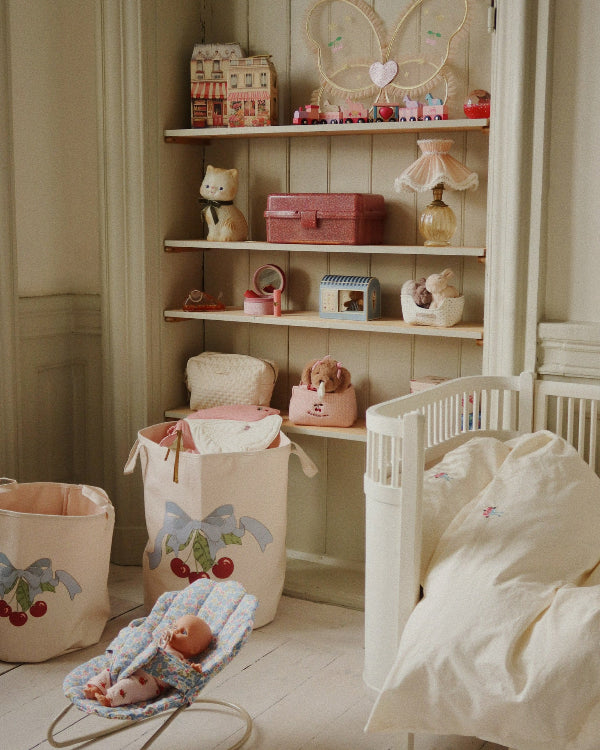 Child gently placing doll in floral bouncer during nurturing pretend play, developing empathy and care skills