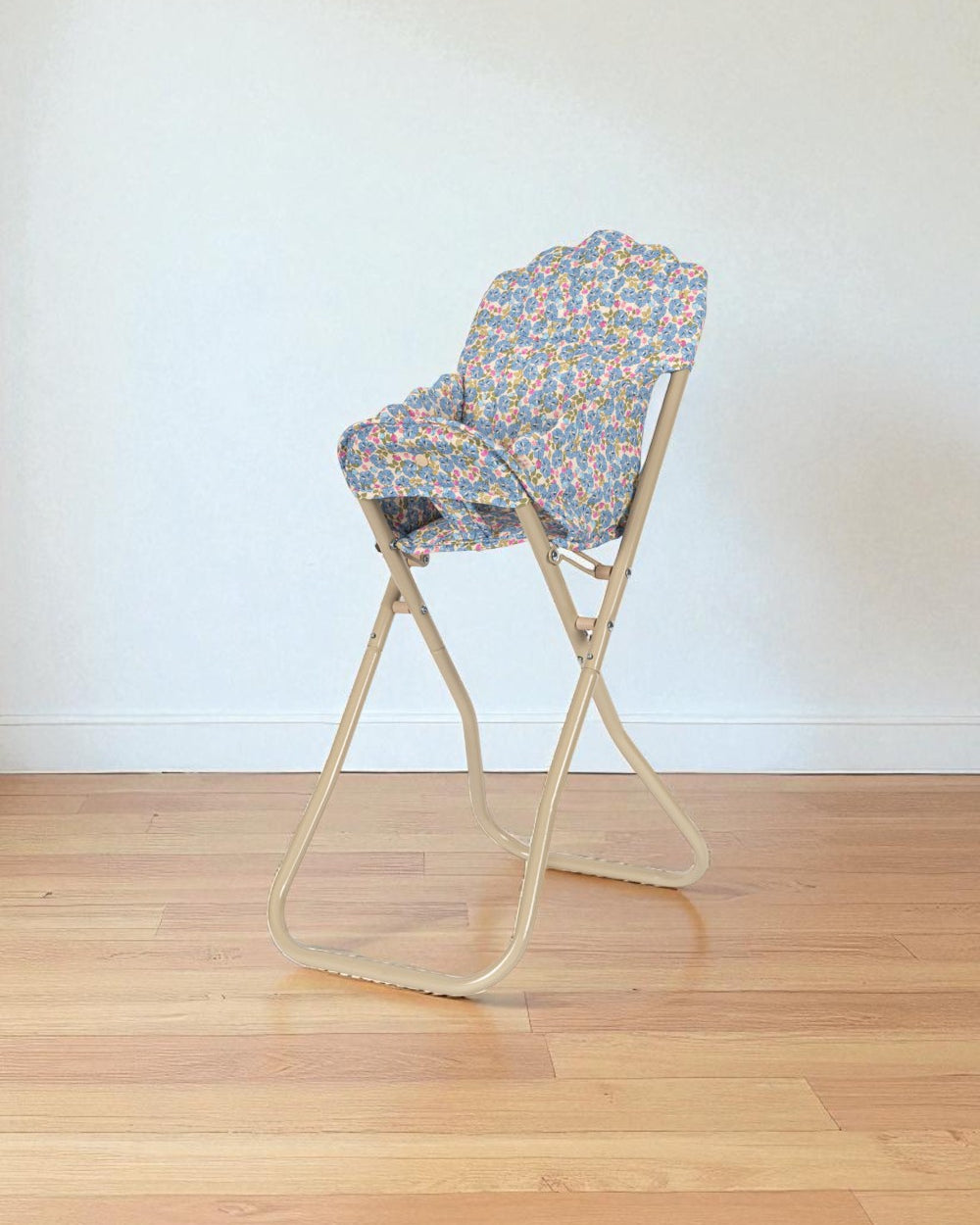 Side view of Fleur Rosier high chair showing foldable champagne metal frame in collapsed position for storage