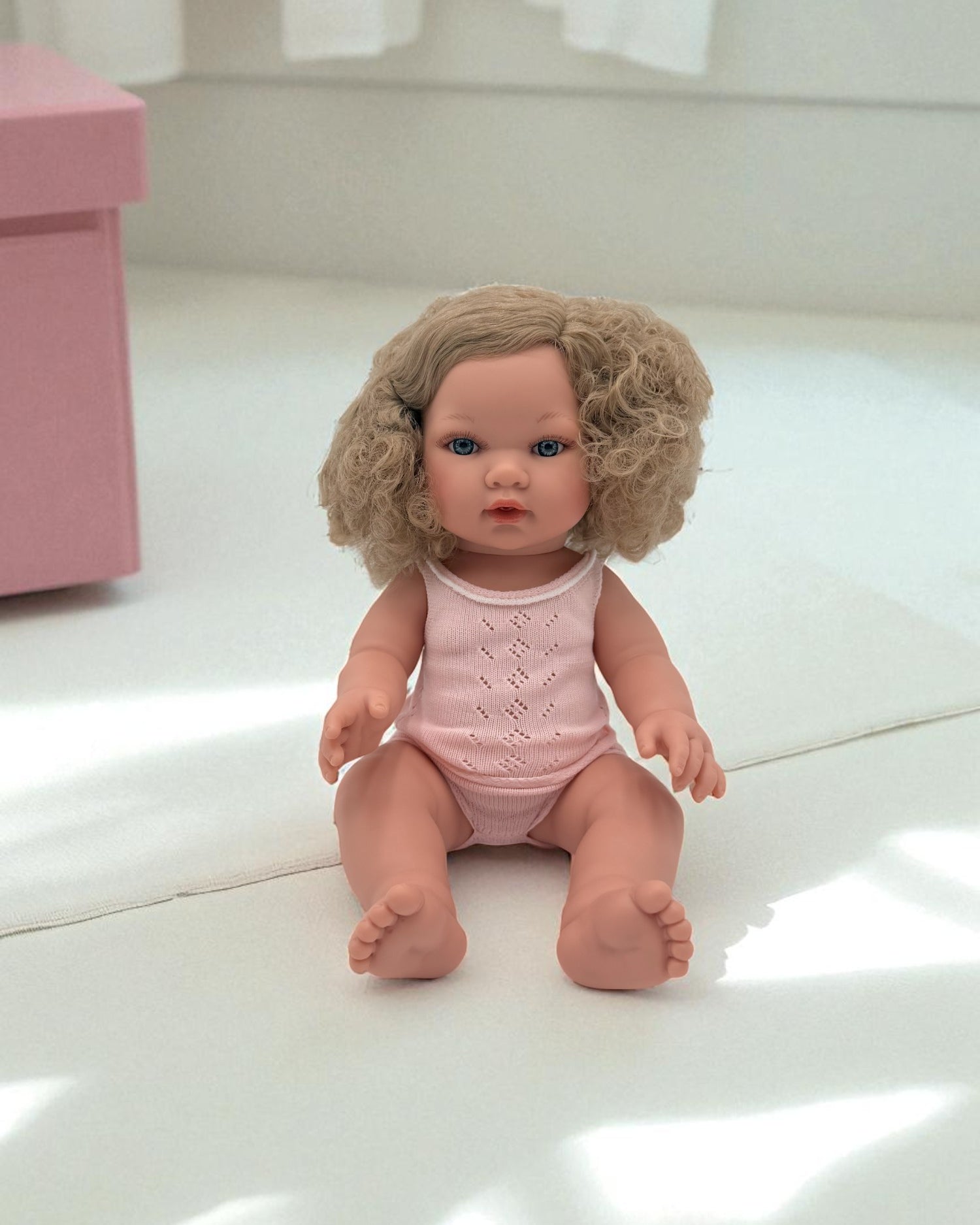Blue-eyed realistic baby doll with curly blonde hair for sensory playroom activities