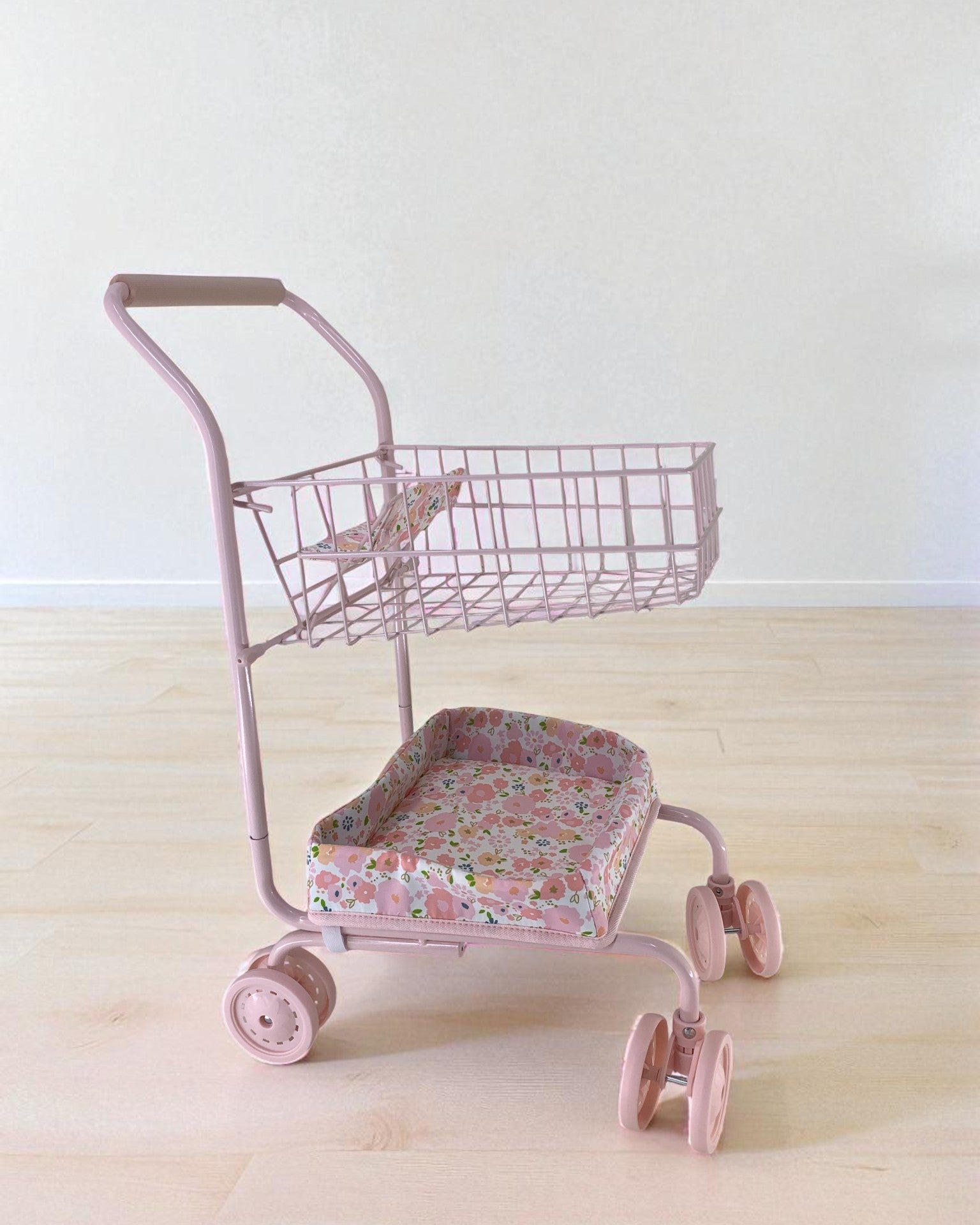 Side view of pink floral doll cart showing two-tier design with upper basket and padded lower seat platform