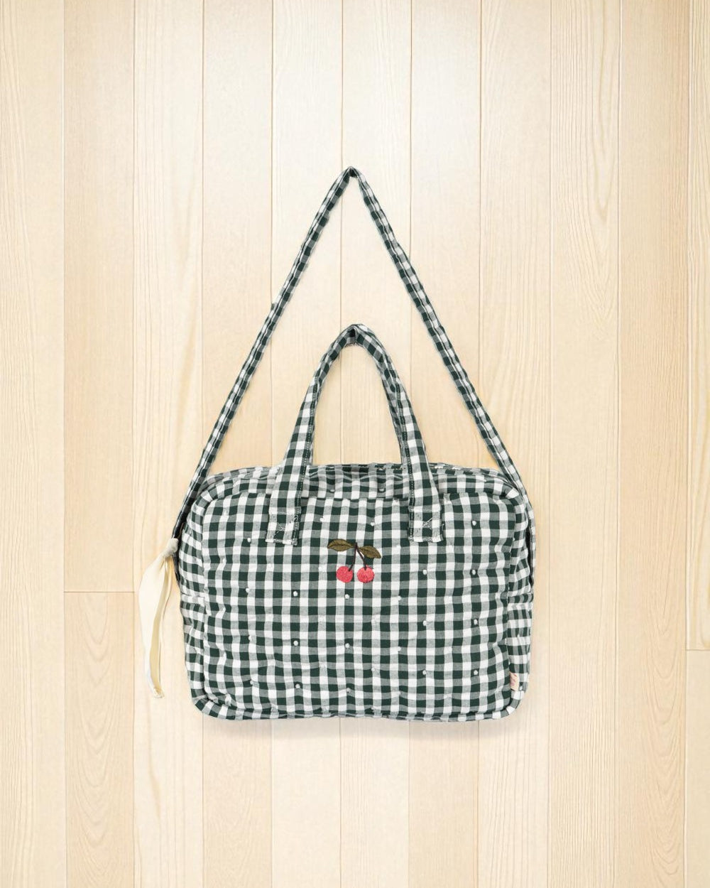 Front view of green and white checkered doll bag with cherry embroidery detail