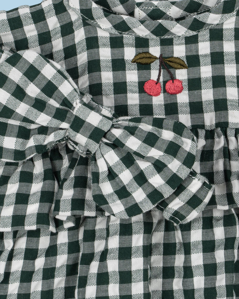 Close-up of embroidered cherry detail on green and white checkered doll dress bodice