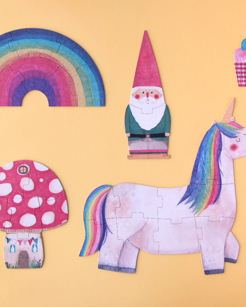 Colorful paper cutouts of a unicorn, mushroom, gnome, rainbow, and cupcake on a yellow background