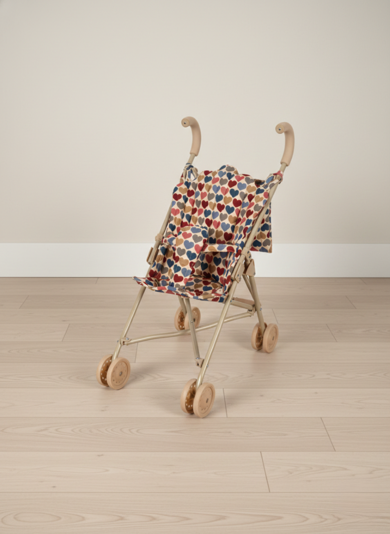 Small baby doll stroller with a colorful patterned cover on a wooden floor.