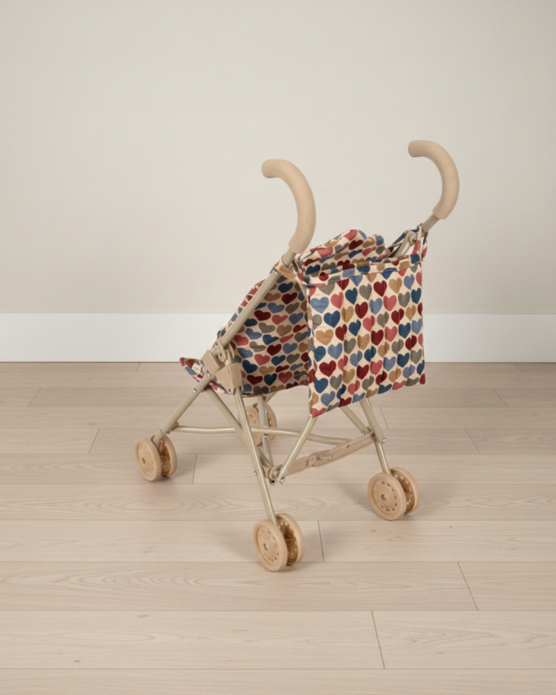 Doll stroller with a patterned cover on a wooden floor