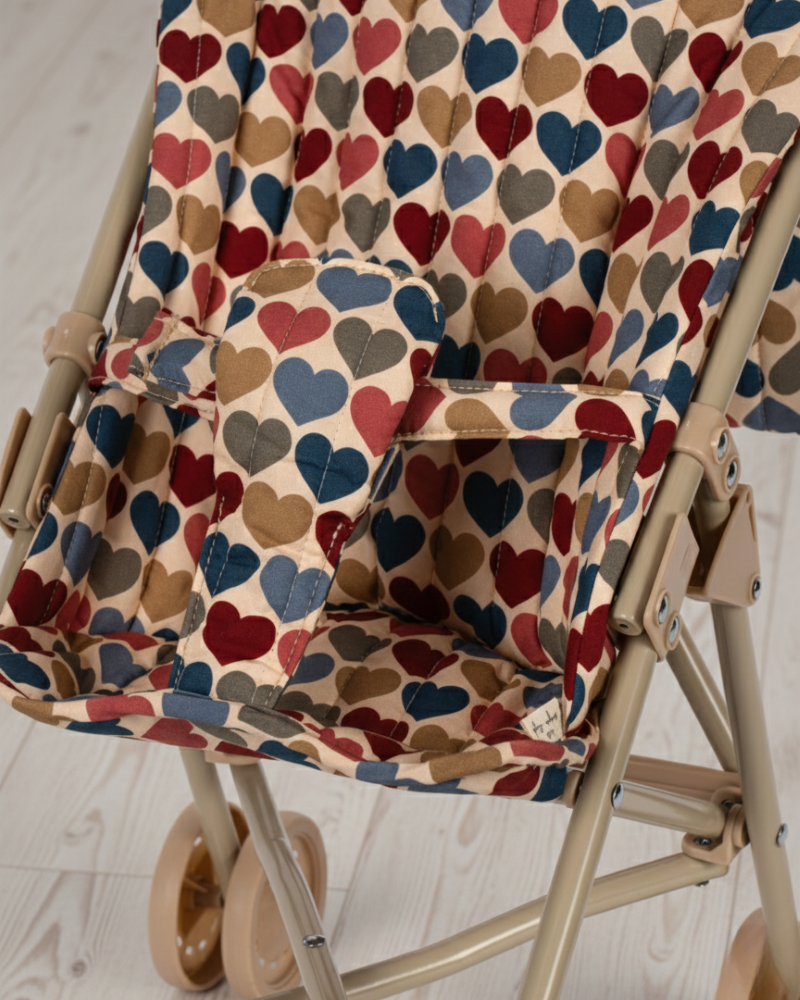 Foldable chair with a colorful heart-patterned cover on a light floor.