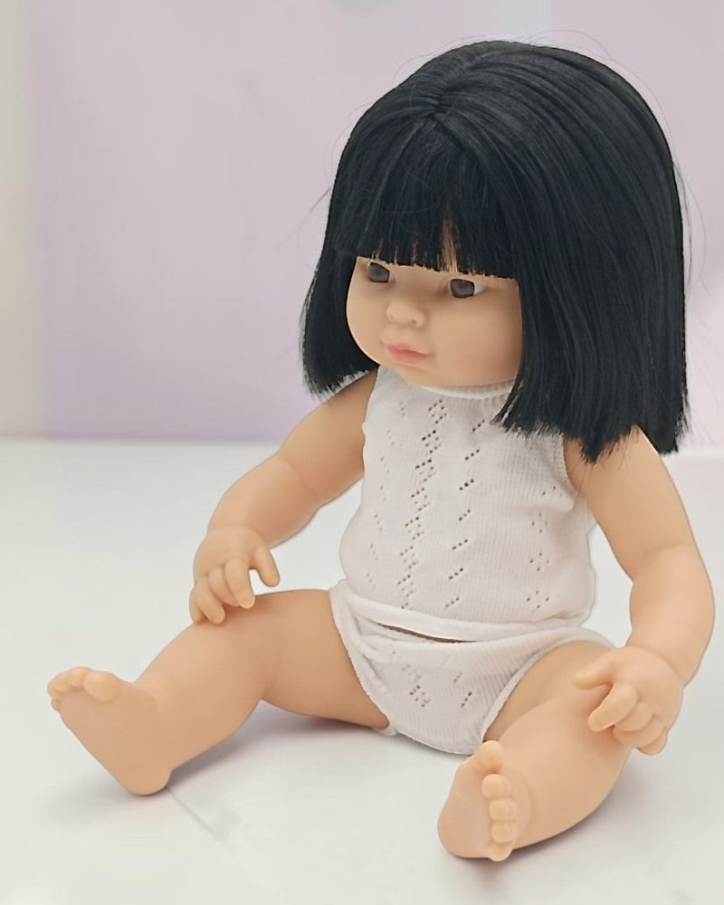 Doll with black hair and a white outfit on a light background