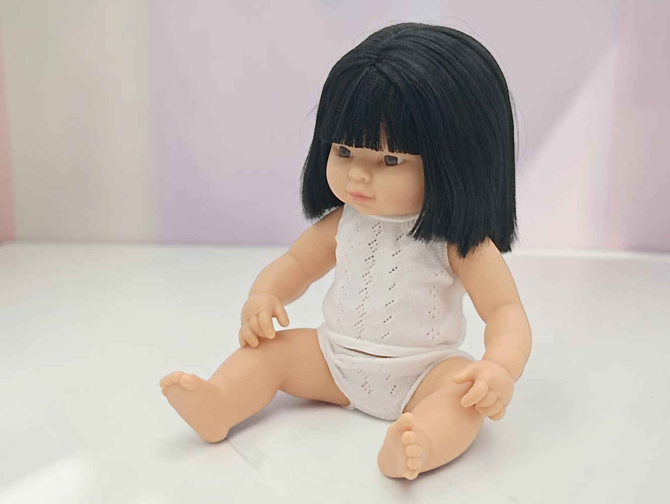 Doll with black hair and a white outfit on a light background