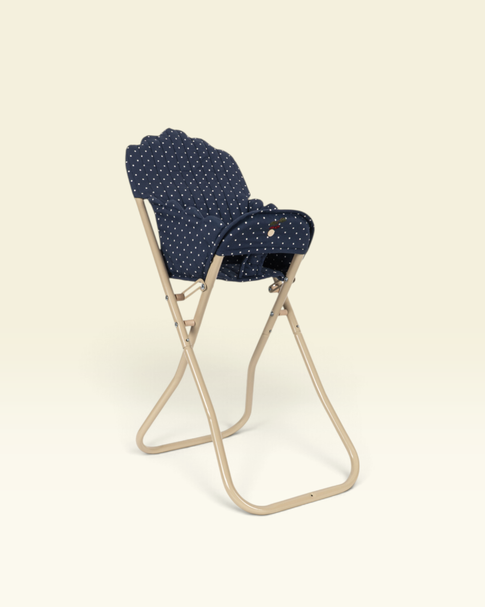 A navy blue fabric chair cushion with small white polka dots, shown on a beige folding chair against a solid cream background.