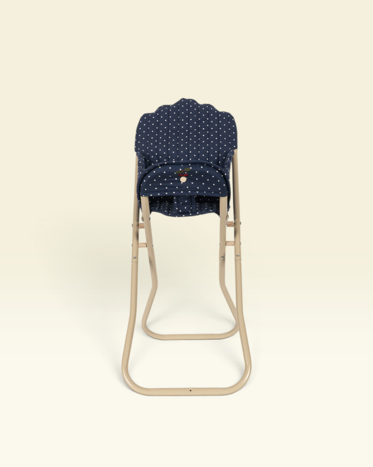 A baby stroller seat insert with a navy blue and white polka dot pattern, shown on a beige metal stroller frame against a solid cream background.