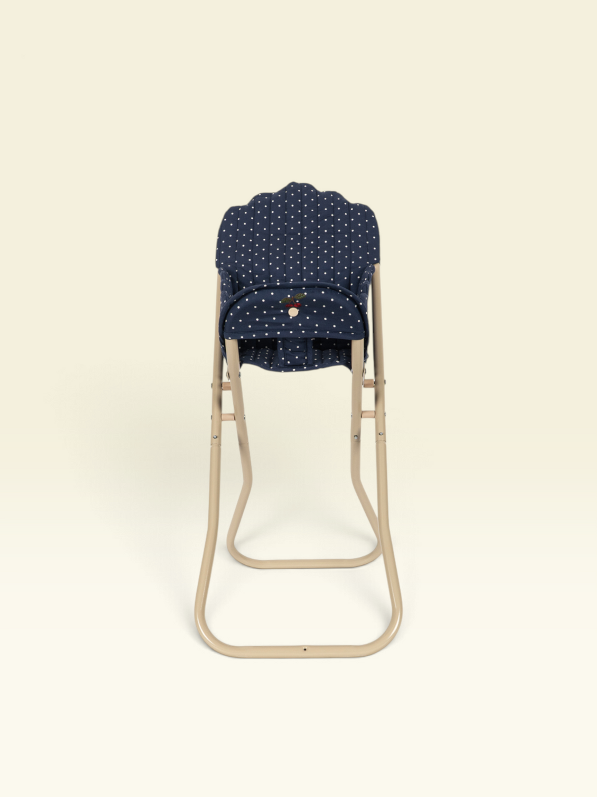 A baby stroller seat insert with a navy blue and white polka dot pattern, shown on a beige metal stroller frame against a solid cream background.