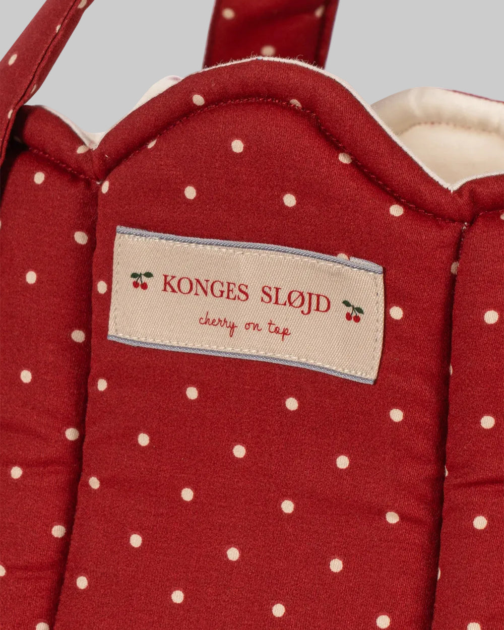 Close-up of Fraise Dot print showing deep berry red fabric with cream polka dots and Konges Sløjd label
