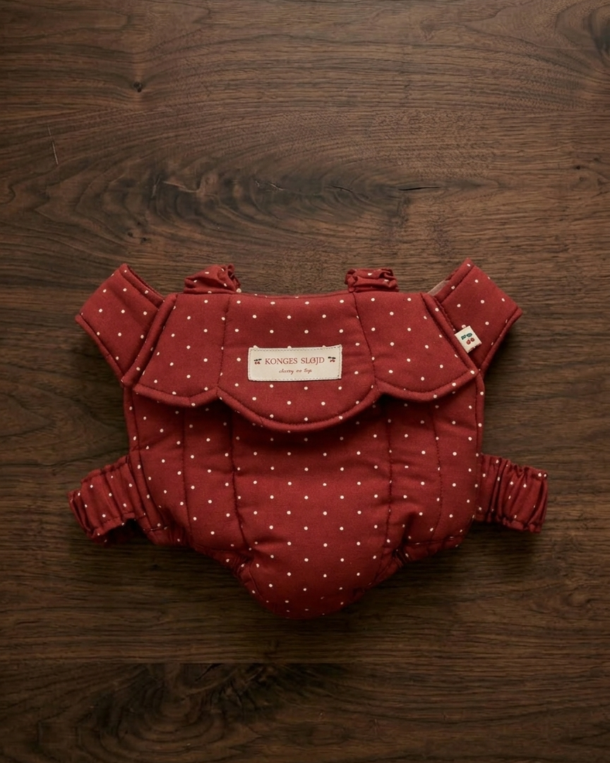 Konges Sløjd baby doll carrier in Fraise Dot berry red polka dot print laid flat on white background
