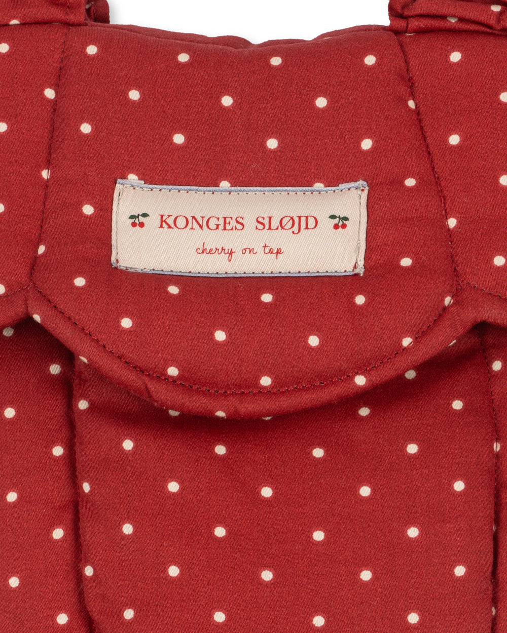 Close-up of Fraise Dot print on carrier showing deep berry red fabric with cream polka dots