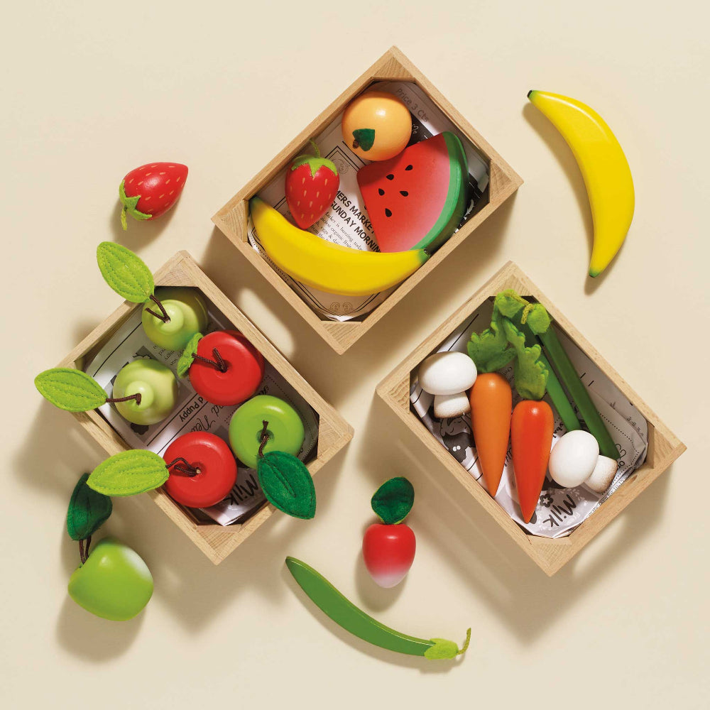 Set of toy fruits and vegetables in wooden boxes on a beige background