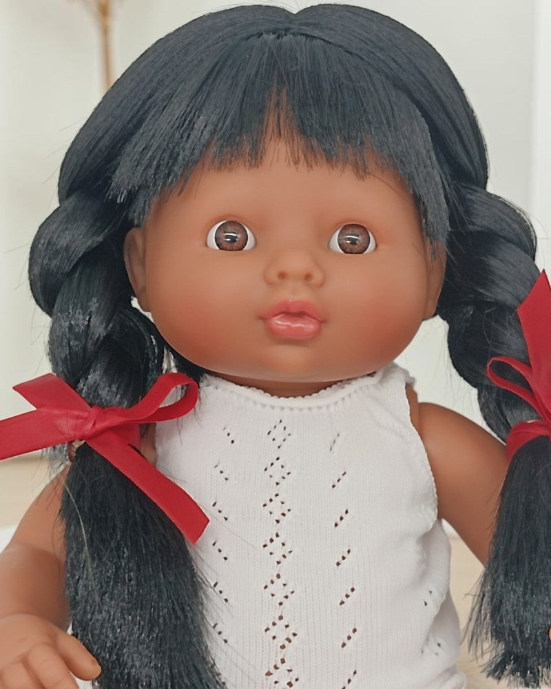 Doll with black hair in pigtails and a white outfit on a light background