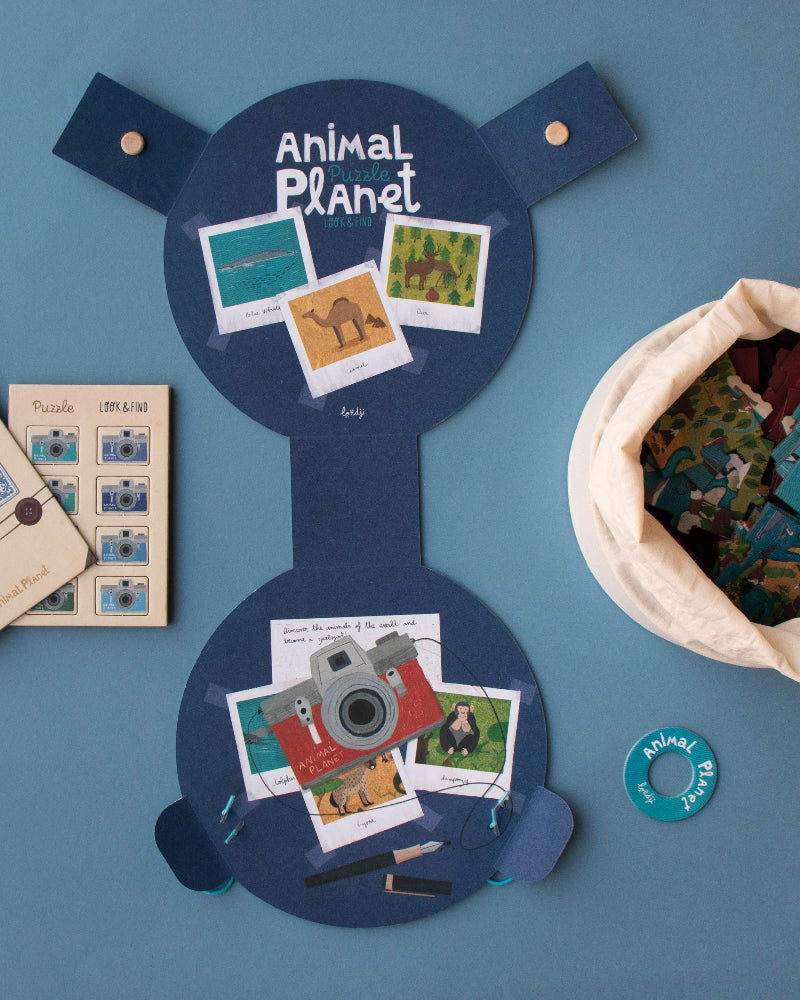 Collection of items including a blue board with 'Animal Planet' branding, photos, and a drawstring bag on a blue background.