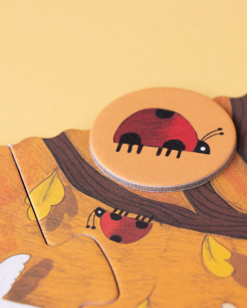 Wooden puzzle piece with a ladybug design on a yellow background